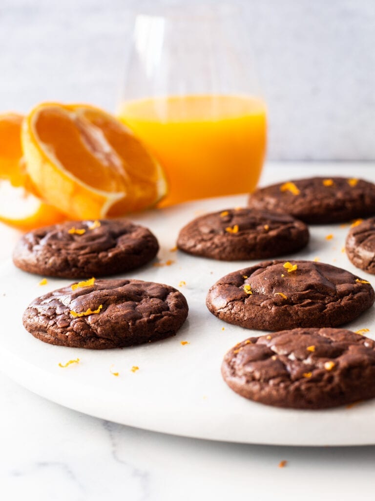 chocolate cookies on a plate with orange and juice in the background