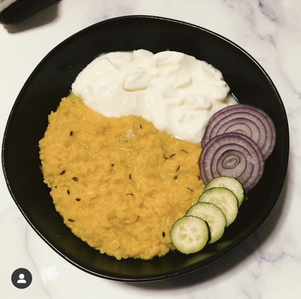 kitchari in a bowl with yogurt, onion and cucumber