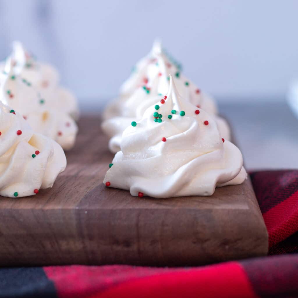 meringue cookies on a wooden plate in a row