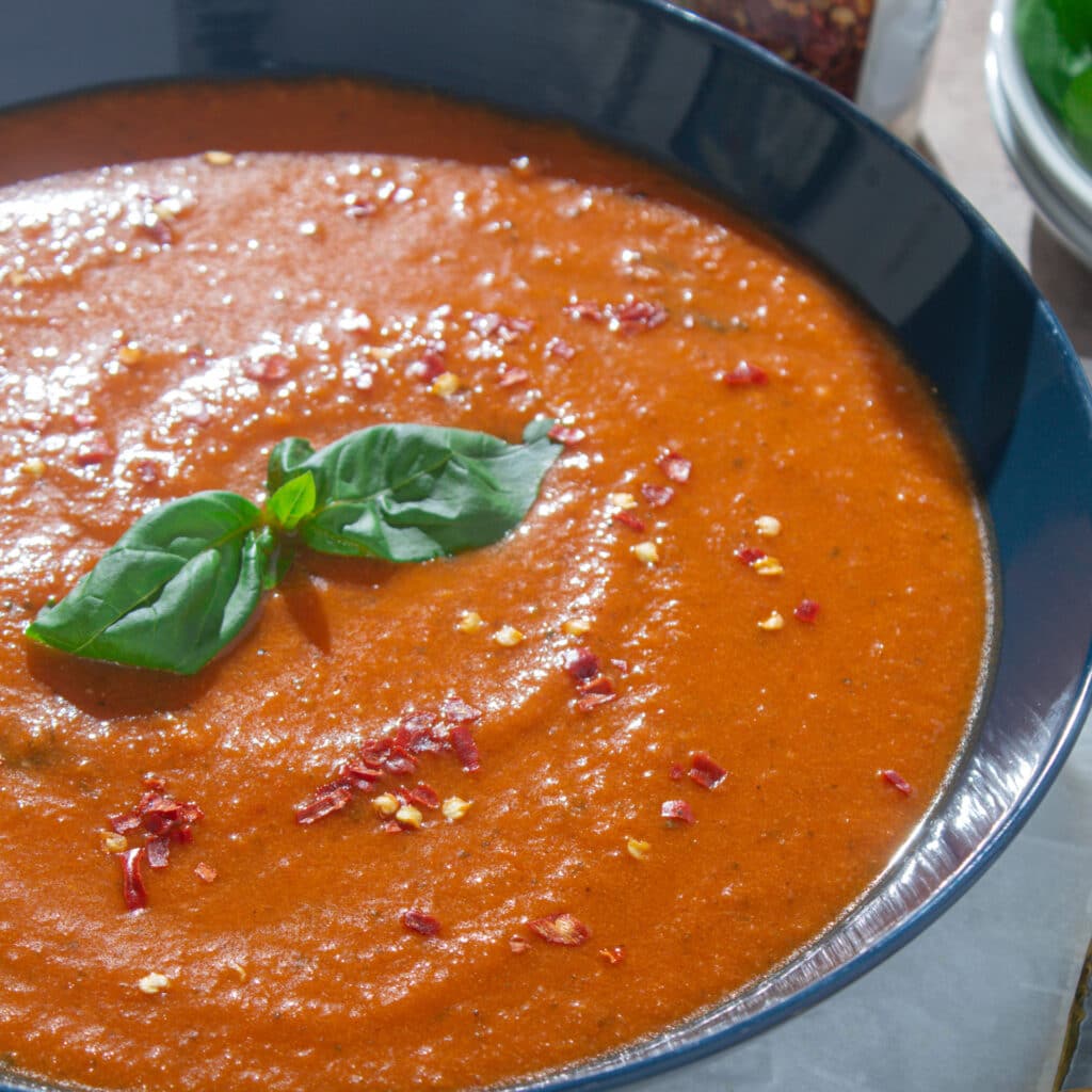 close up of soup with basil and chili flakes garnishing
